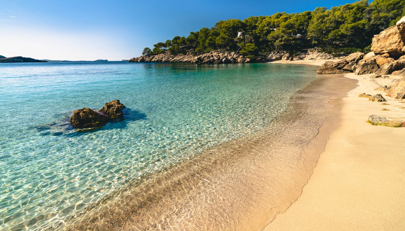 Strand von Cala Saladeta mit der Insel Illa Conillera im Hintergrund